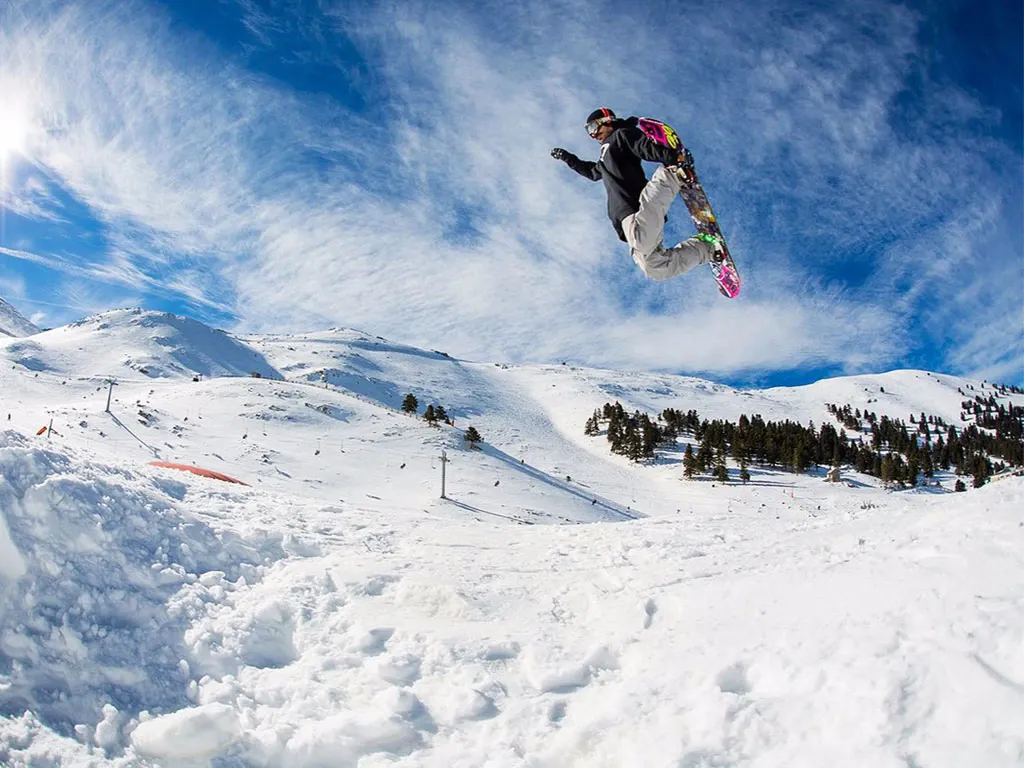 Snowboarder jumping at Kalavryta Ski Resort on Mount Helmos, Greece winter destination