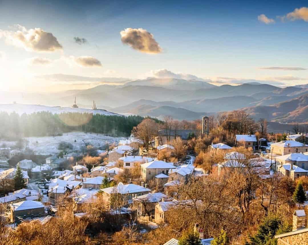 Snow-covered houses and mountains in Florina town, Northern Greece, during winter sunrise