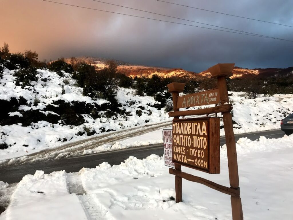 Snowy road in Pelion mountain, Magnesia, Greece with traditional tavern sign