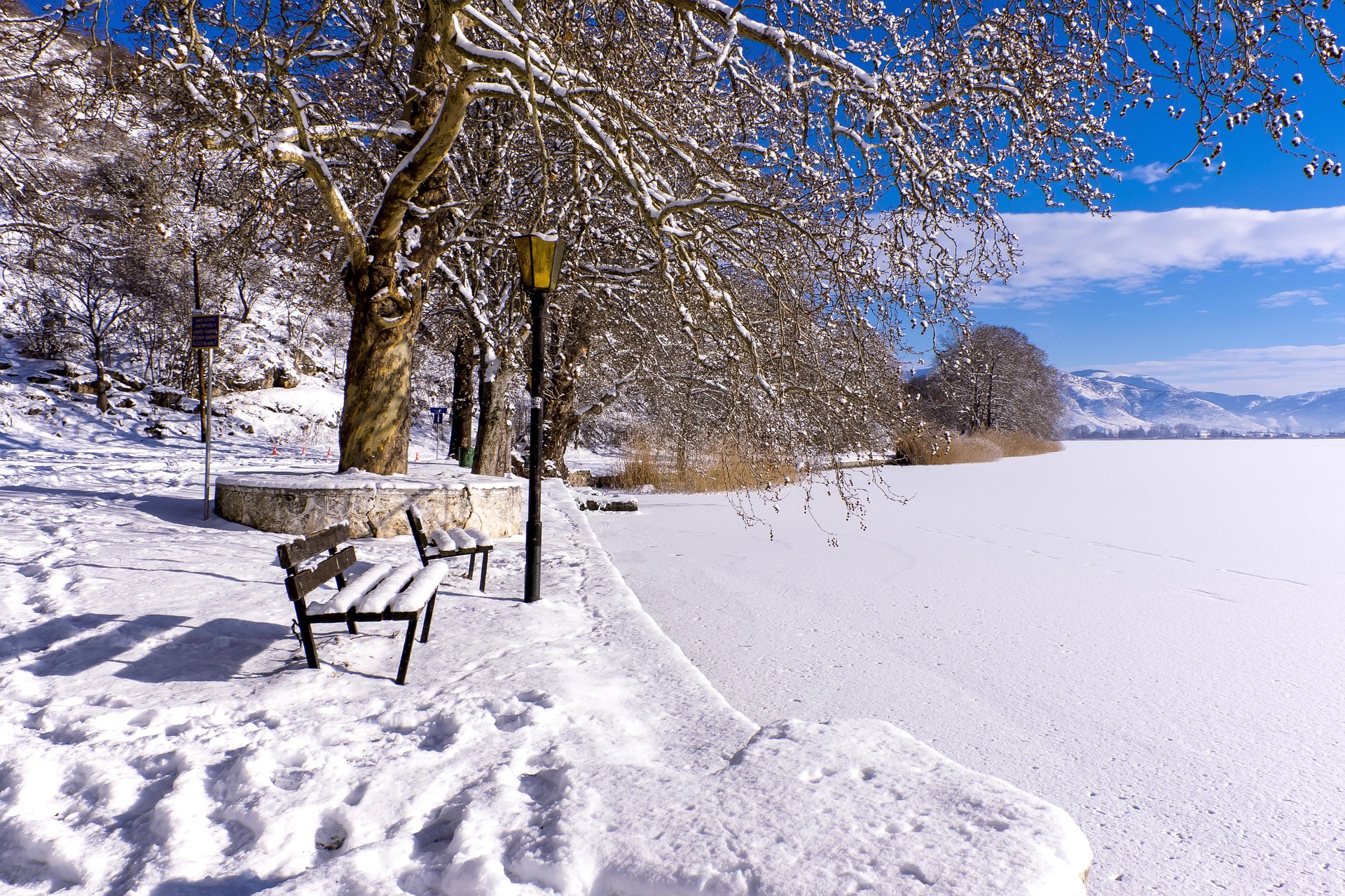Snowy Ioannina lake with bench and trees during winter in Greece